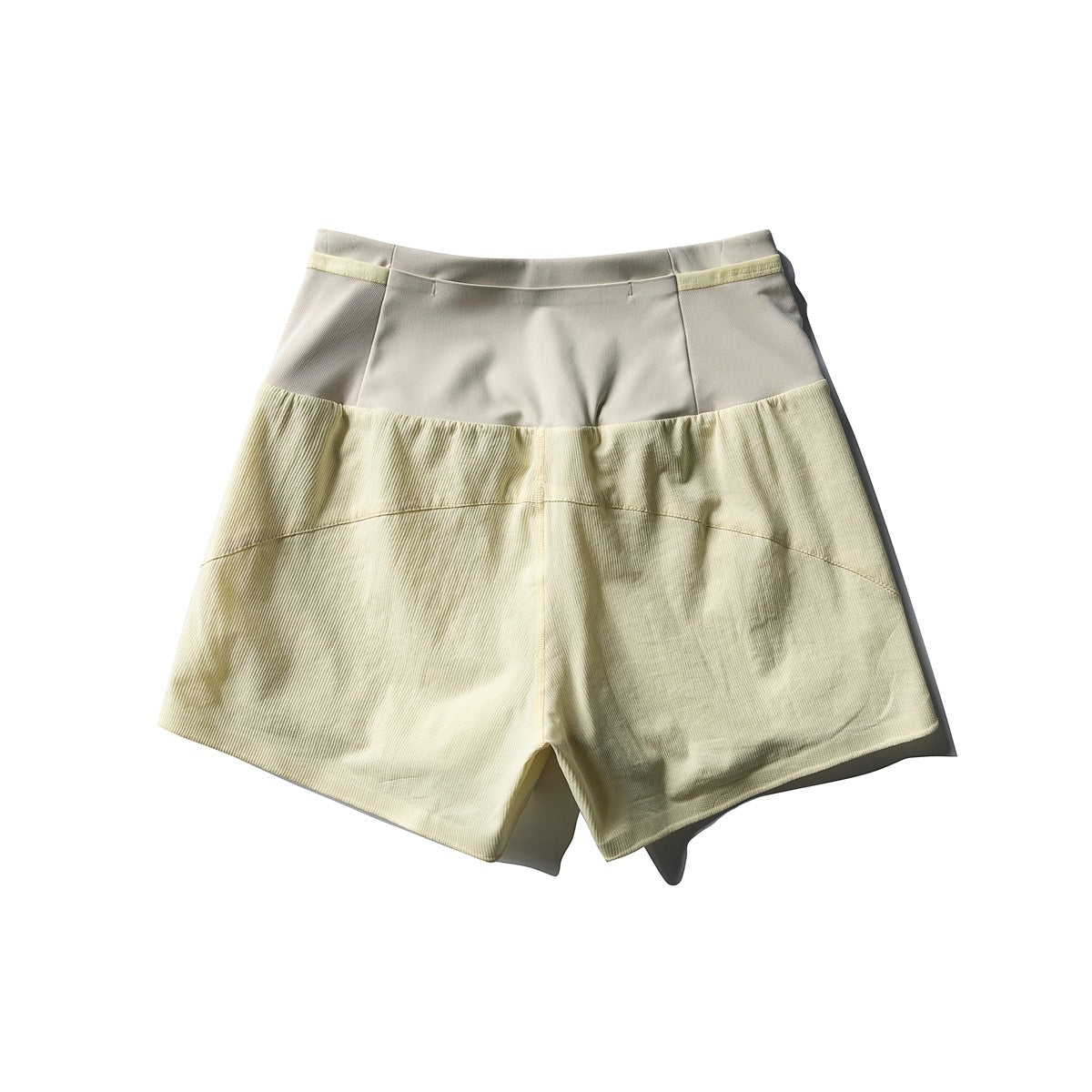 Pale yellow shorts with a cream waistband and textured lower panels, shown from the front.
