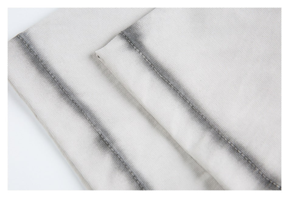 Close-up of stitched seams and overlapping folds on light gray fabric.