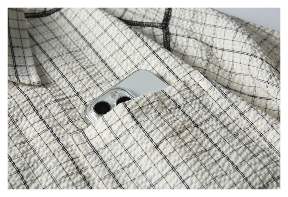 Close-up of a chest pocket on a cream-and-black checked shirt, with a phone tucked inside.