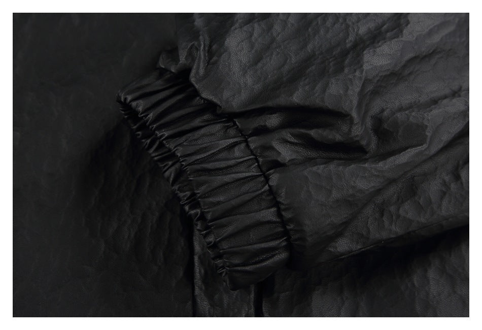Close-up of a black jacket sleeve with a gathered elastic cuff and crinkled surface.