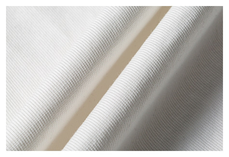 Macro view of white ribbed garment fabric folded into soft ridges.
