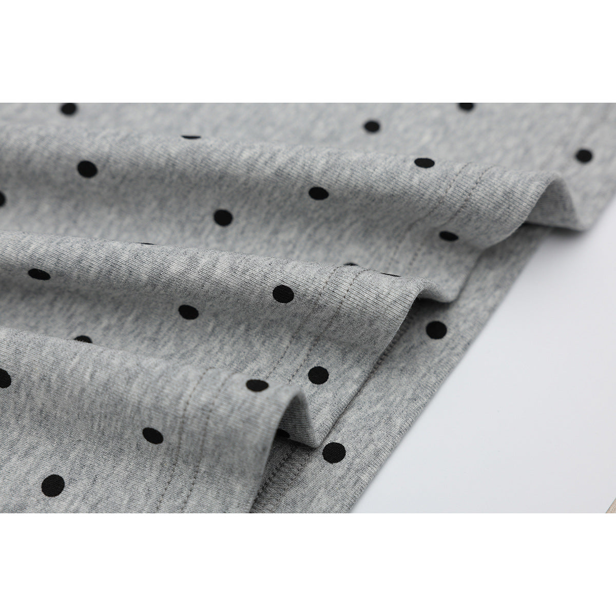 Close-up of the gray heather polo's black polka-dot fabric and stitched hem folds.