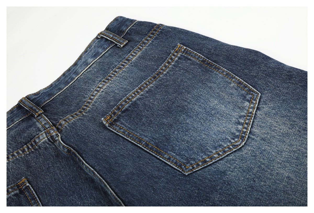 Close-up of a back pocket on dark blue jeans with contrast stitching and faded denim.