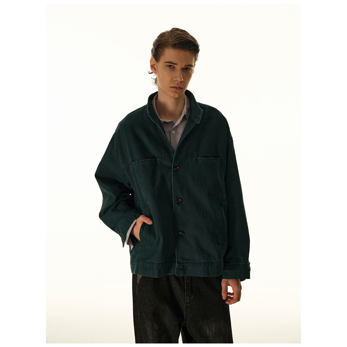 Front view of a model wearing a dark teal button-front jacket over a mauve shirt and black trousers.