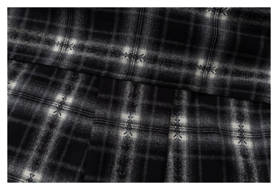 Close-up of a seam and gathered fabric on a black and gray plaid shirt.