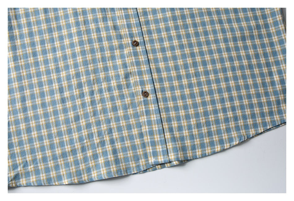 Close-up of the plaid shirt's lower front hem and button placket.