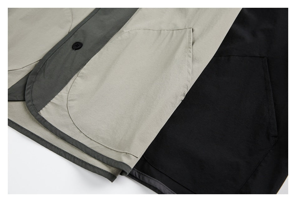 Close-up of overlapping light gray and black garments, showing contrast trim, a button, and large patch pockets.