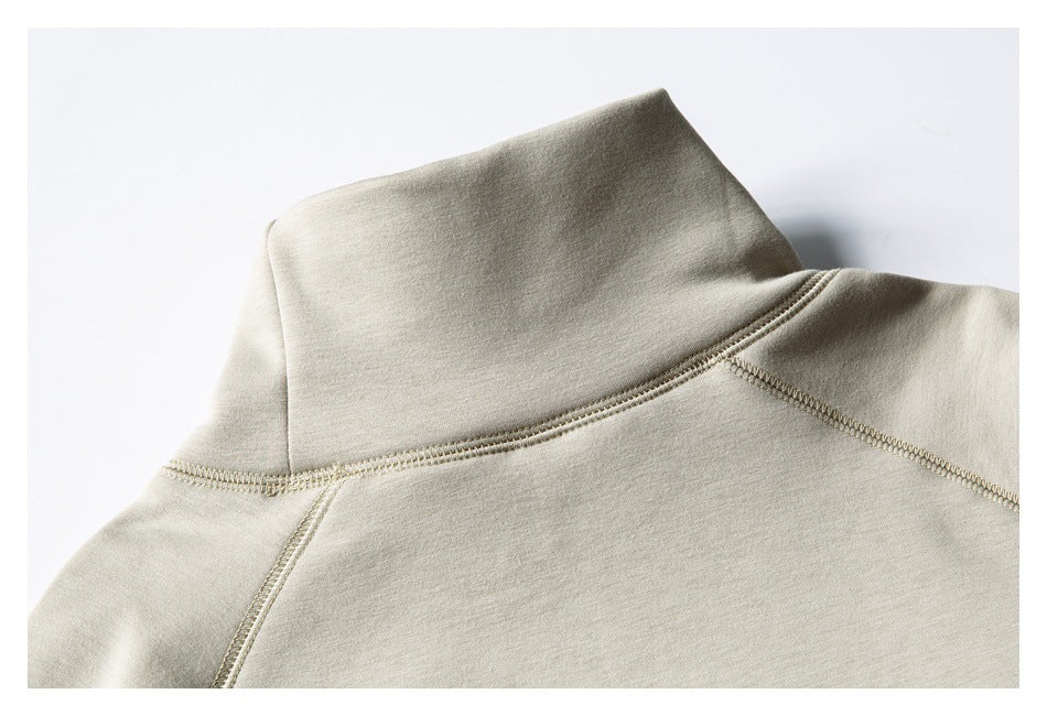 Close-up of a light beige garment's high collar and stitched shoulder seams.