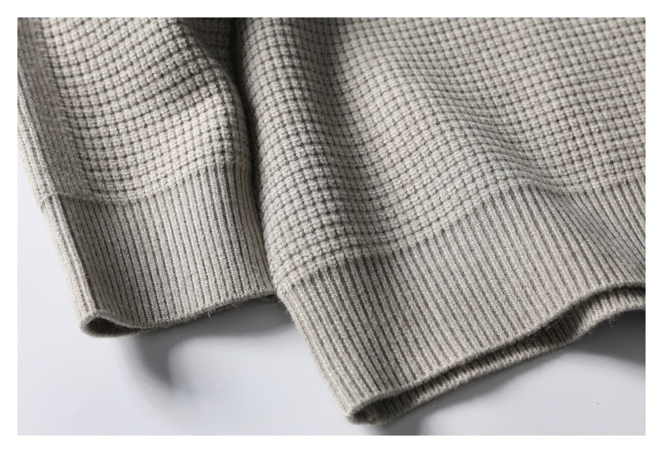 Close-up of a light gray textured knit garment with wide ribbed cuffs.