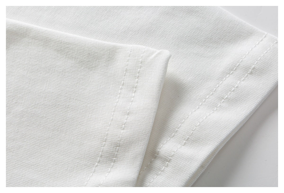 Close-up of white garment fabric showing a folded edge and parallel stitching.