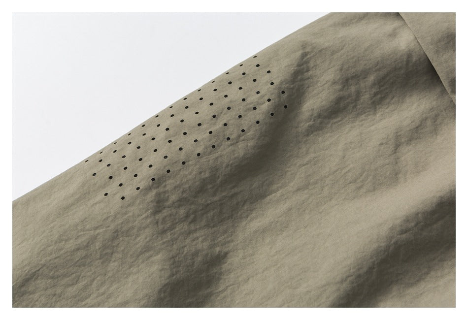 Close-up of small black dotted detailing on taupe fabric.