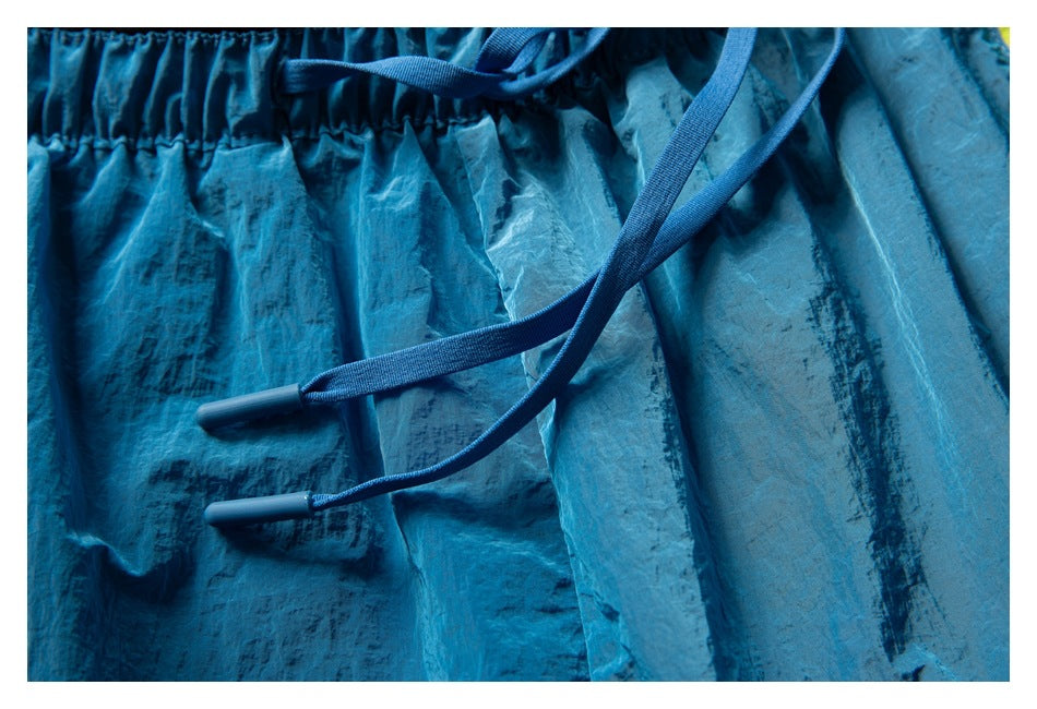 Close-up of the gathered waistband and blue drawstrings on turquoise patterned running shorts.