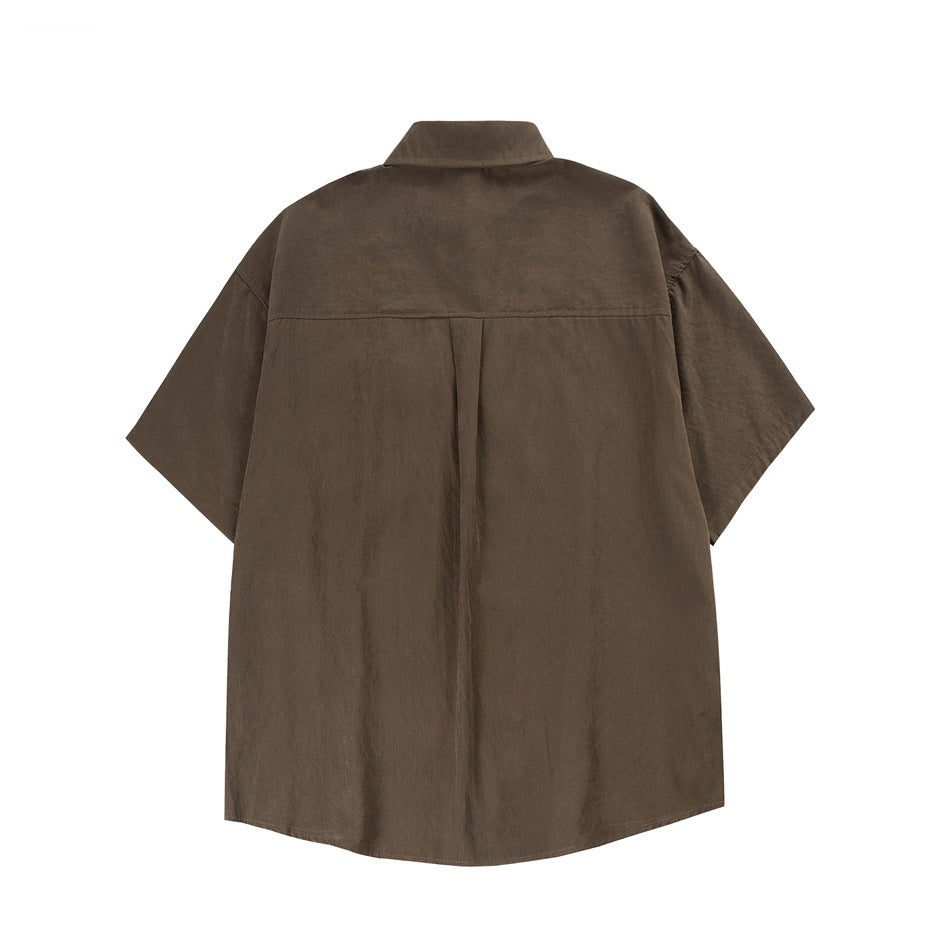 Back view of a dark brown oversized short-sleeve collared shirt with a center pleat.