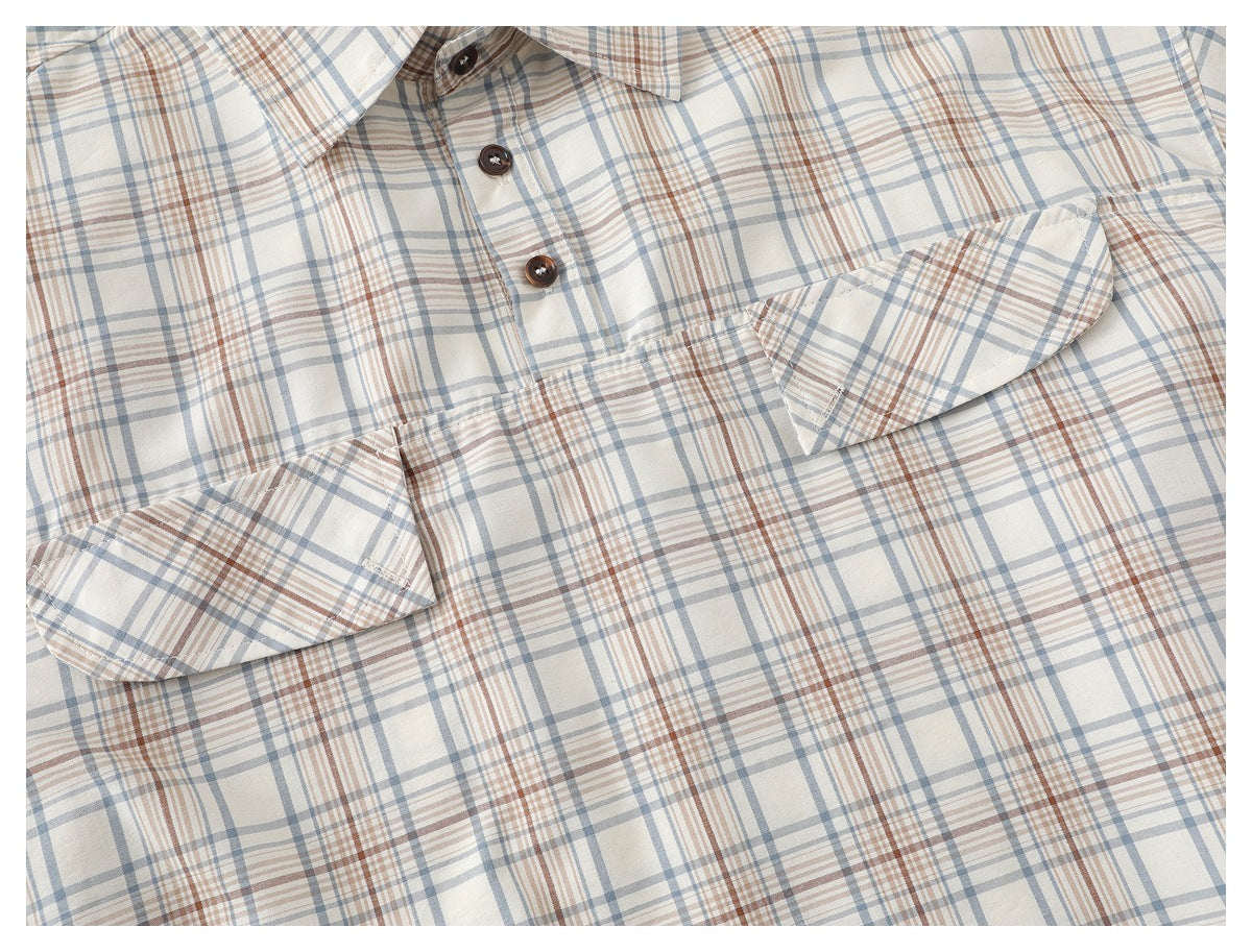 Close-up of an ivory plaid shirt front with a button placket, collar, and flap chest pockets.