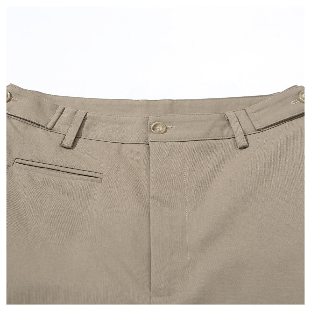 Close-up of taupe trousers showing the waistband button, belt loops, front seam and welt pocket.