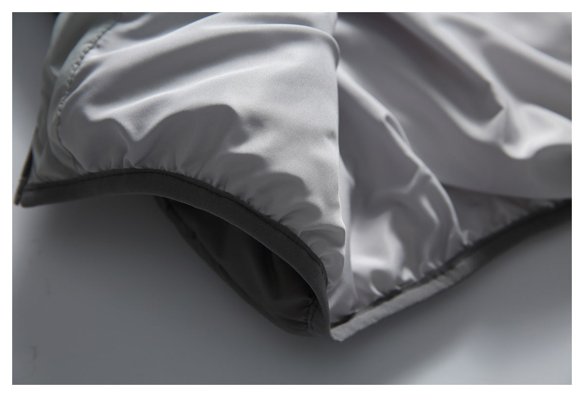 Close-up of a light gray padded jacket edge with dark binding and curved stitching.