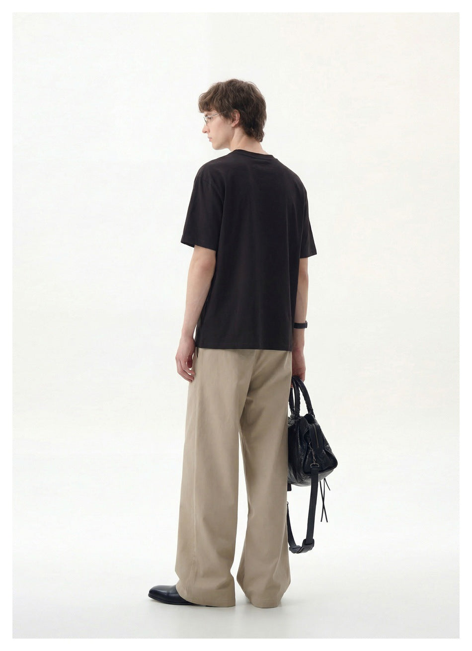 Rear view of a model wearing a plain black crew-neck T-shirt with beige wide-leg trousers.