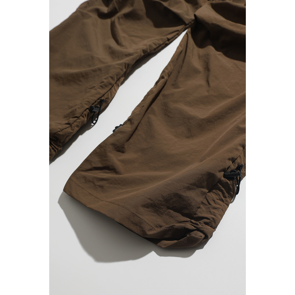 Close-up of brown cargo pant legs with adjustable drawcords at the hems.