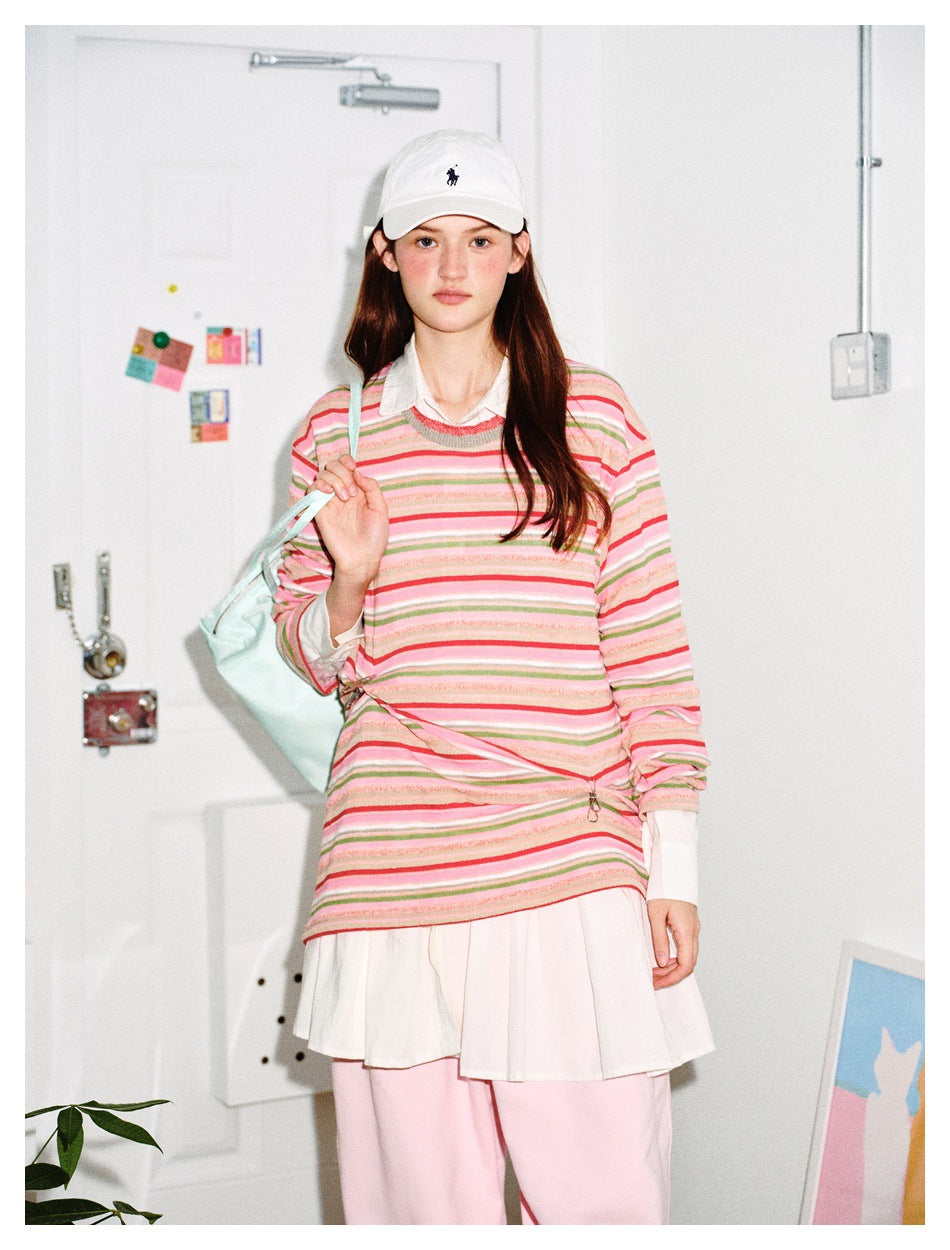 Model in pink multicolor striped crew neck top over a white collared shirt, with white cap and pink pants