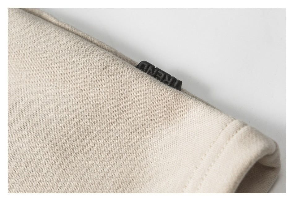 Close-up of beige fabric edge with a small black raised label bearing indistinct lettering.