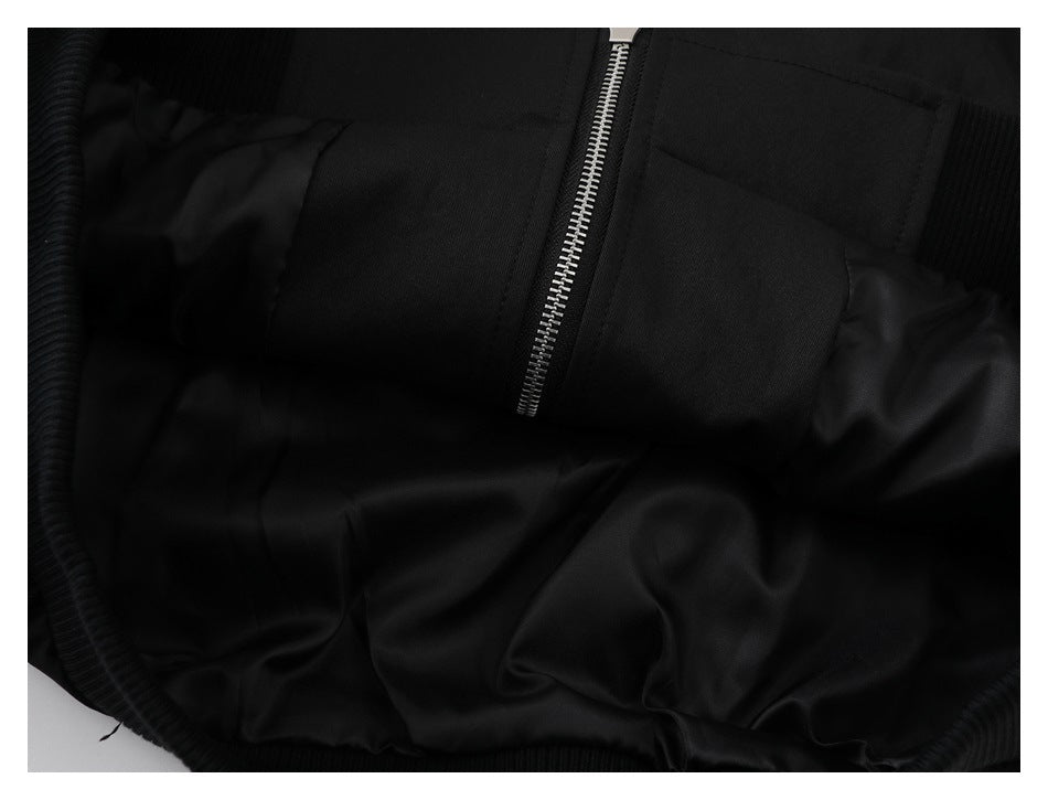 Close-up of a black jacket's silver front zipper, pocket stitching, and dark inner lining.