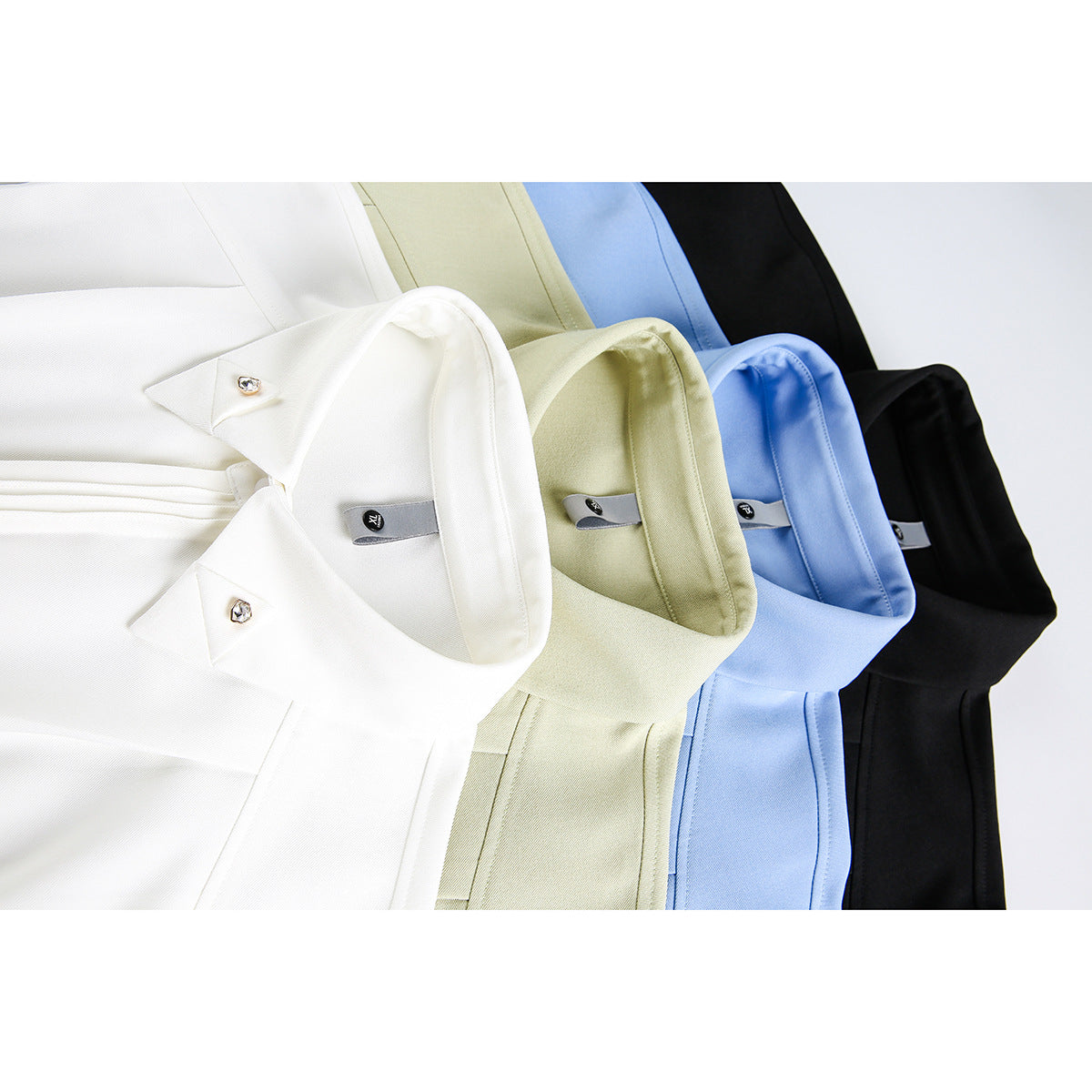 Close-up of four collared shirts in white, pale green, light blue, and black, showing jeweled collar buttons.