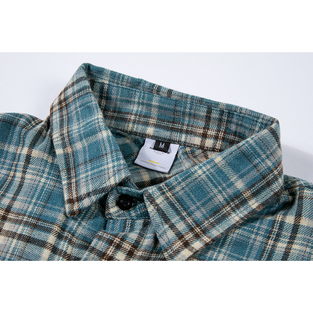 Close-up of a blue, cream, and brown plaid shirt collar with a black button and visible size tag.