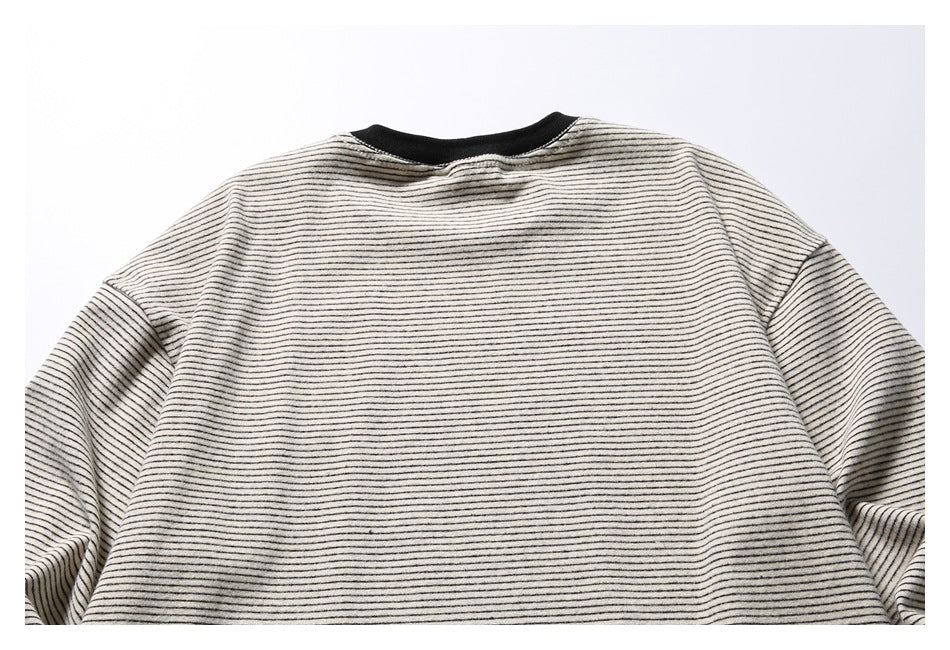 Flat-lay back view of a cream top with thin black stripes and a black ribbed crew neckline.