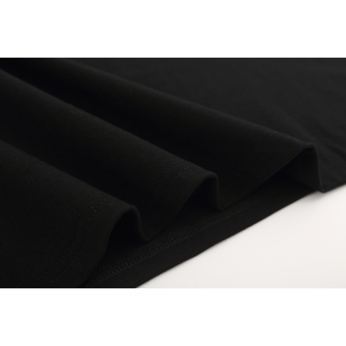 Close-up of the black T-shirt's folded fabric and stitched hem.