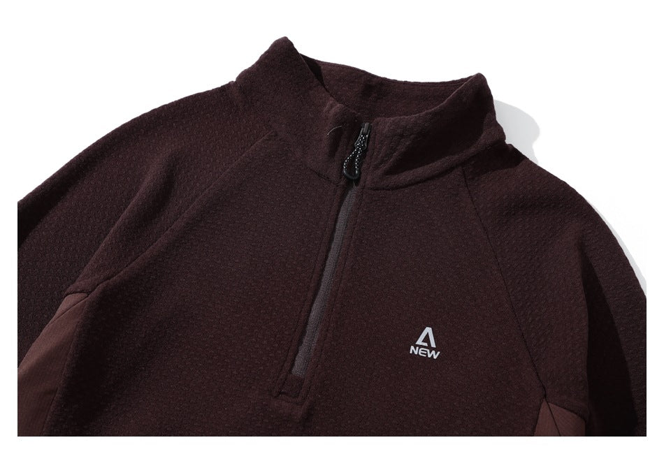 Close-up of the burgundy pullover's stand collar, quarter zipper, textured fabric, and small chest logo.