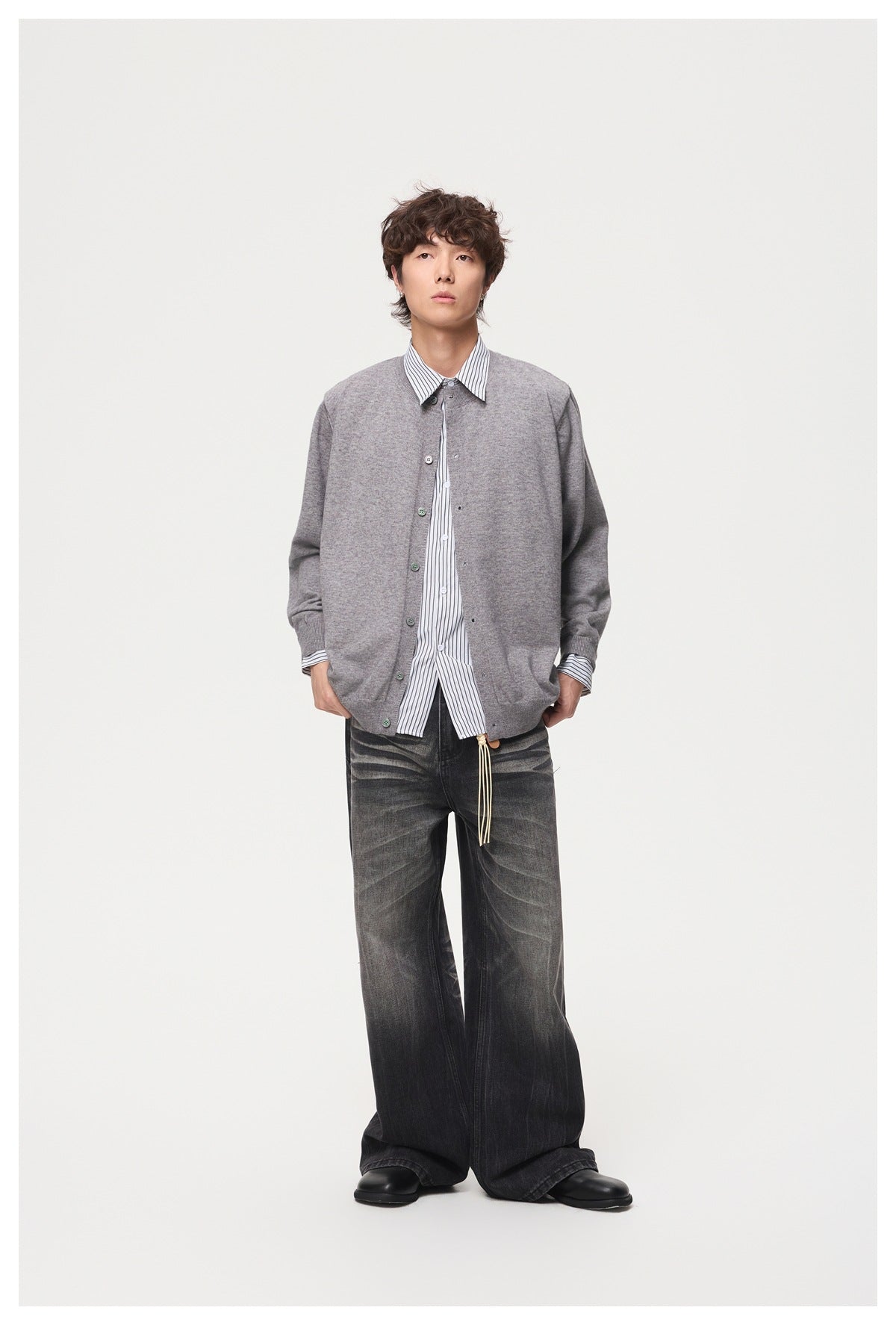 Model wearing a gray button-front knit cardigan over a striped shirt with wide-leg faded black jeans, full-length view