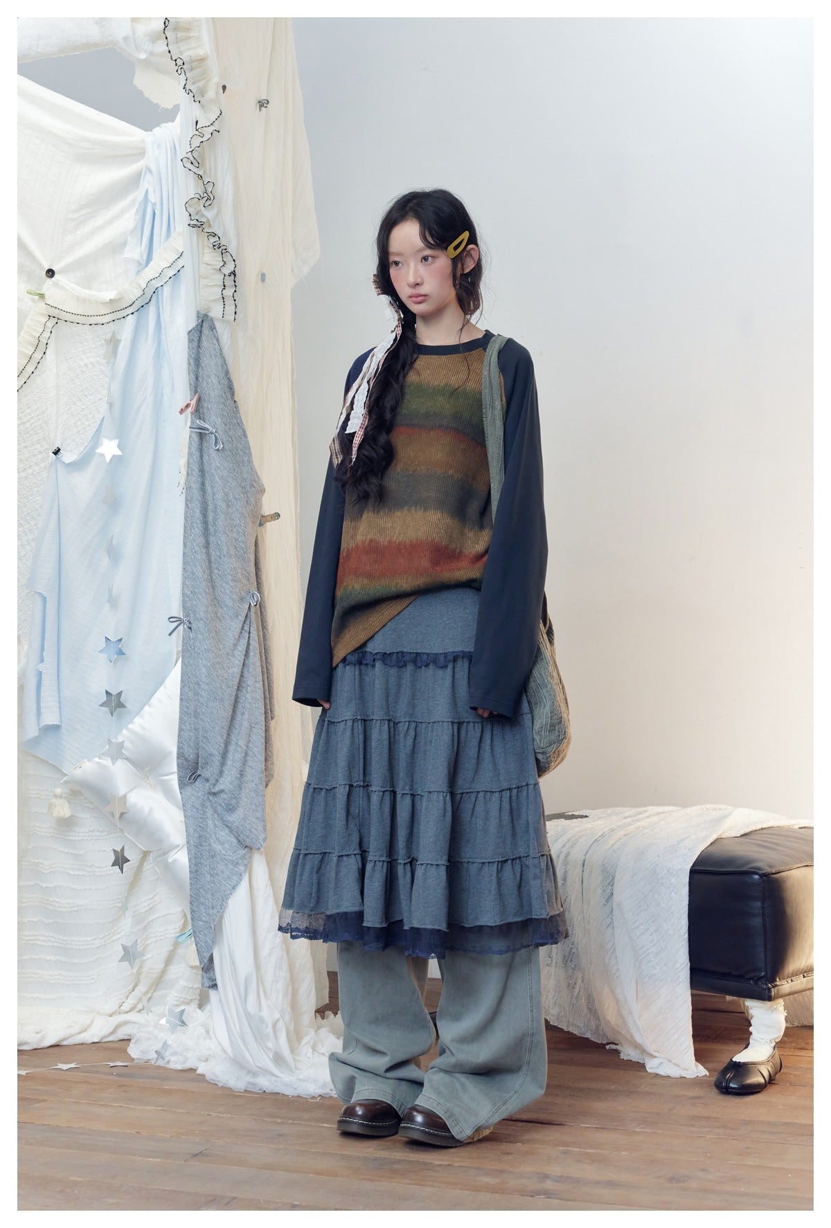 Model in navy striped raglan long-sleeve top with a tiered skirt and wide-leg pants, three-quarter view