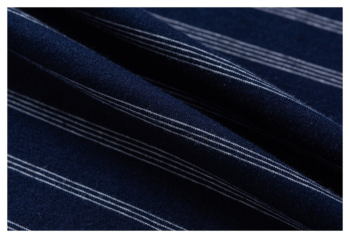 Close-up of dark navy fabric with thin parallel white stripes, folded into soft ridges.