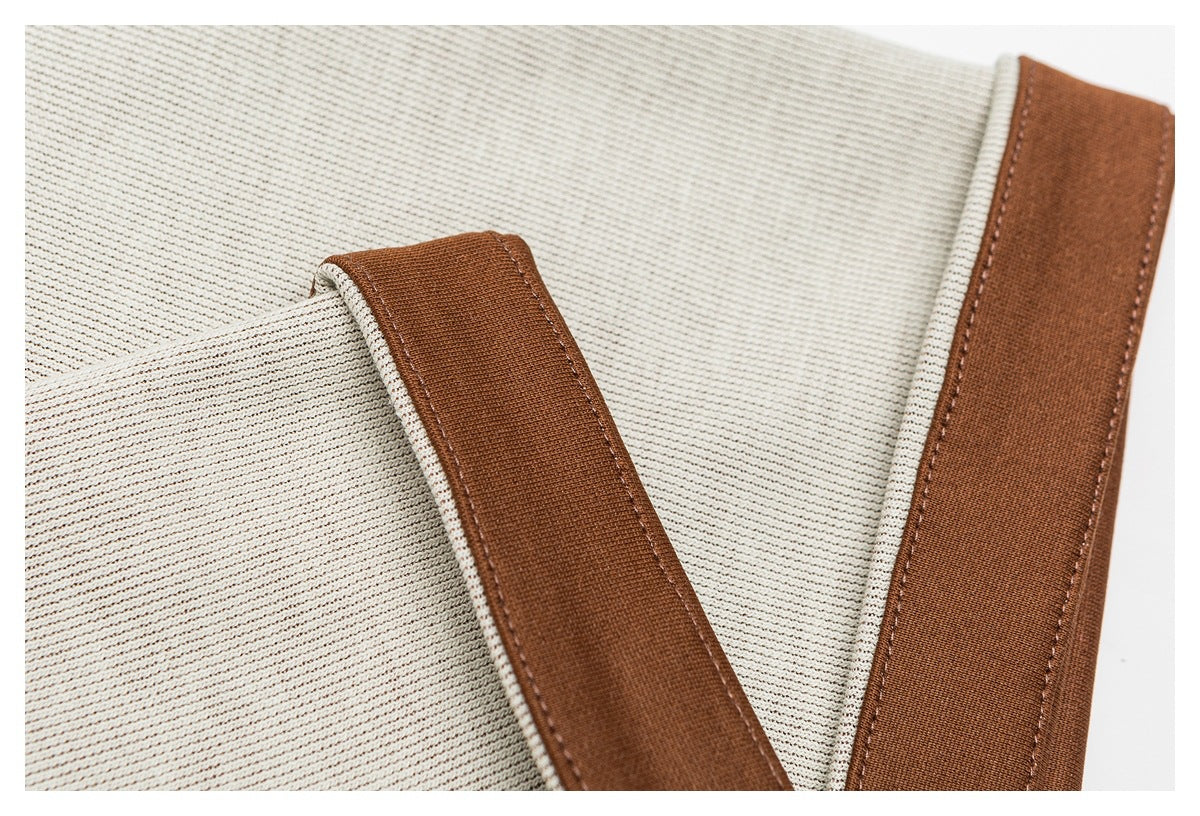 Close-up of cream ribbed fabric with wide brown trim and visible stitching.