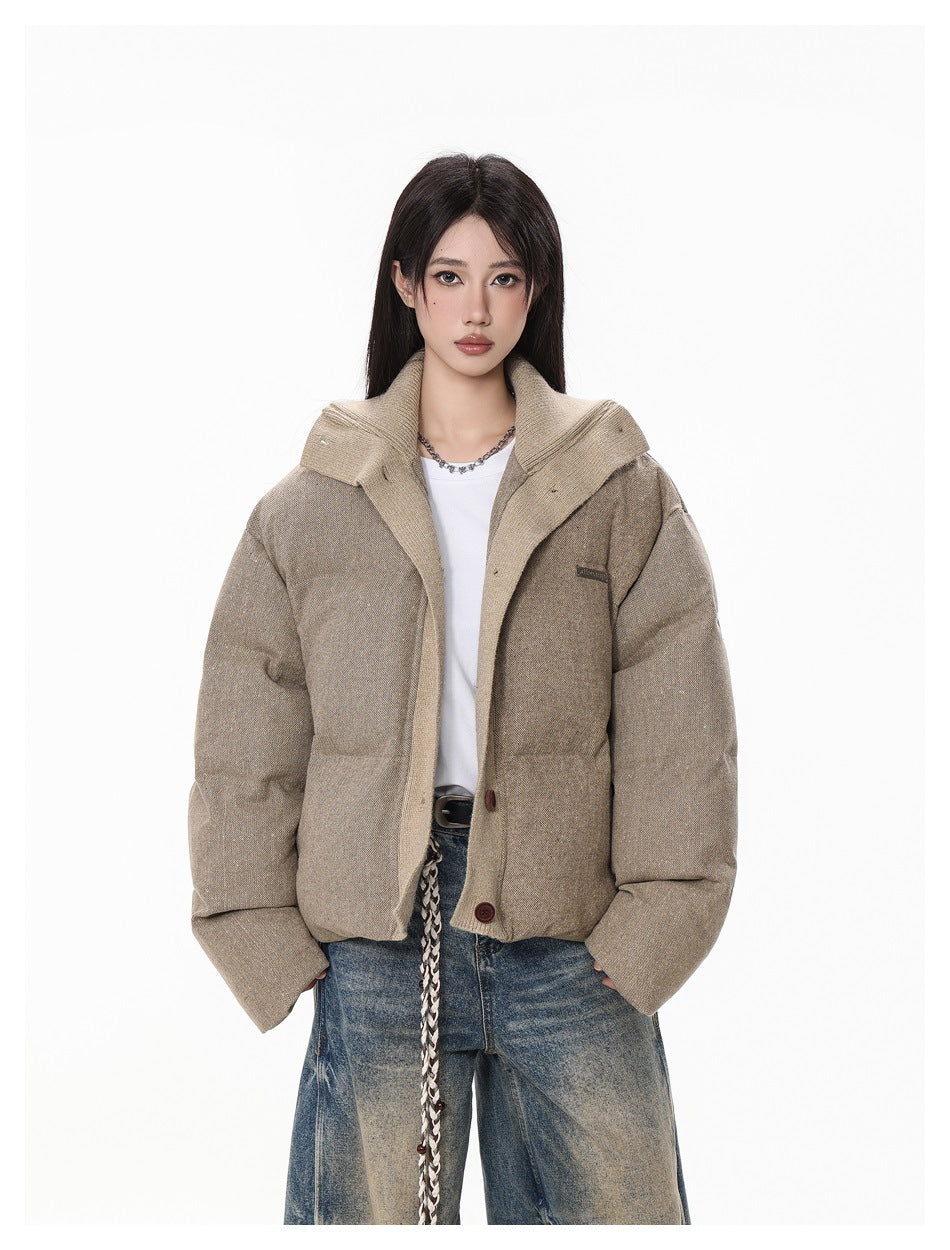Front view of a model wearing a taupe padded jacket with a wide collar and dark buttons.