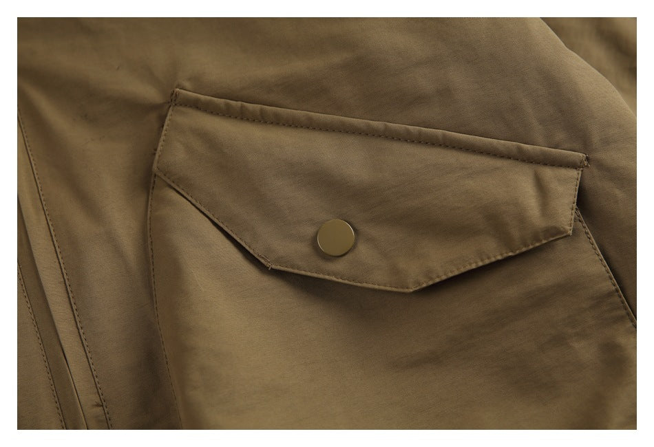 Close-up of a khaki jacket flap pocket with a round snap button and visible stitching.