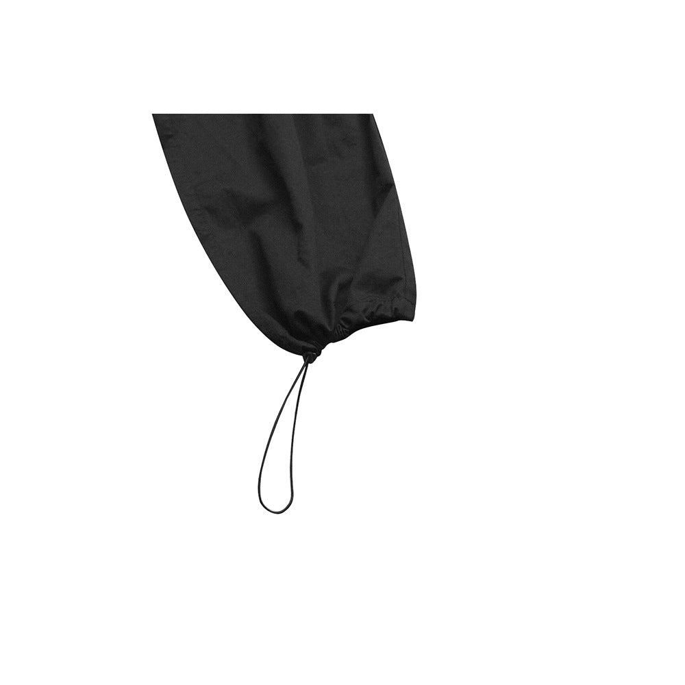 Close-up of a black pant leg with an elasticized cuff and dangling drawcord loop.