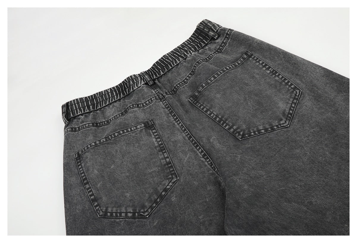 Close-up of charcoal gray jeans showing the elastic waistband and two rear pockets.