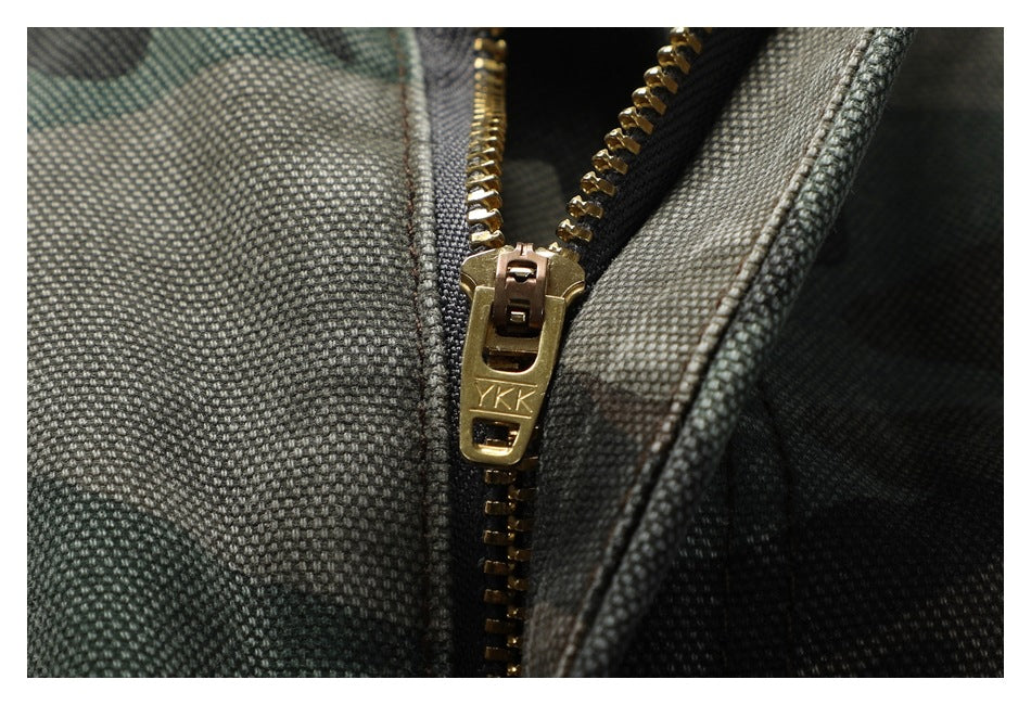 Macro view of a brass-colored zipper on camouflage trousers, with YKK lettering on the pull.