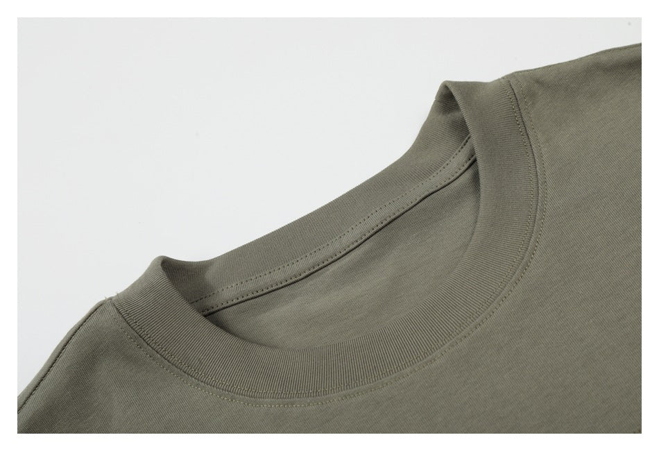 Close-up of the ribbed crew neckline and shoulder seam of a muted olive-gray T-shirt.