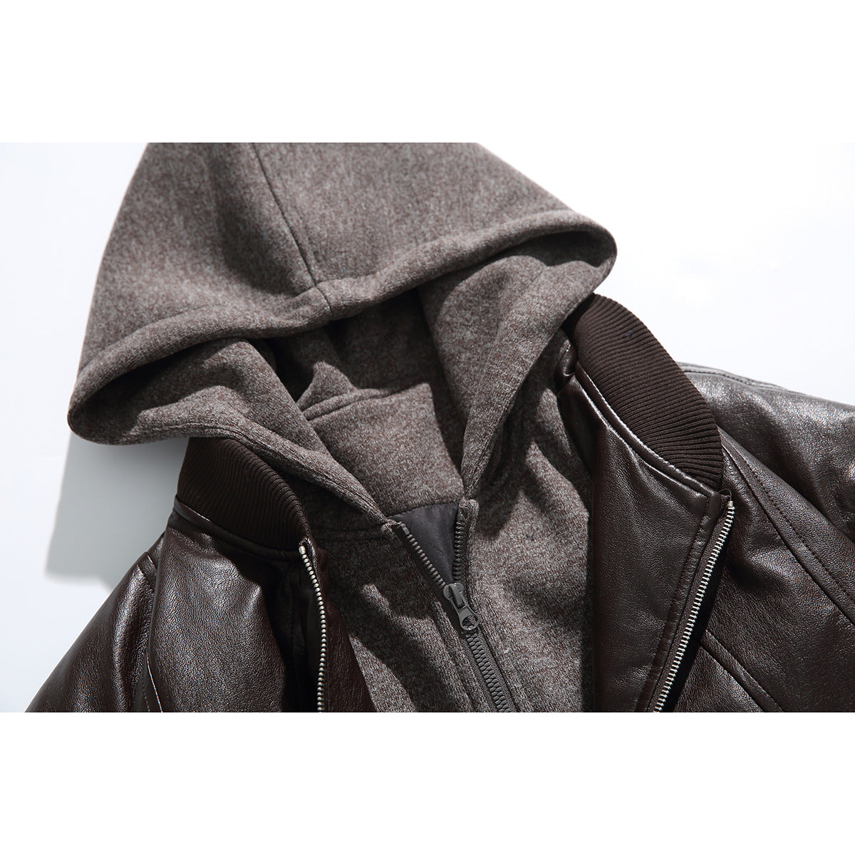 Close-up of a dark brown jacket layered over a gray zip-up hoodie, showing the hood, collar, and zippers.