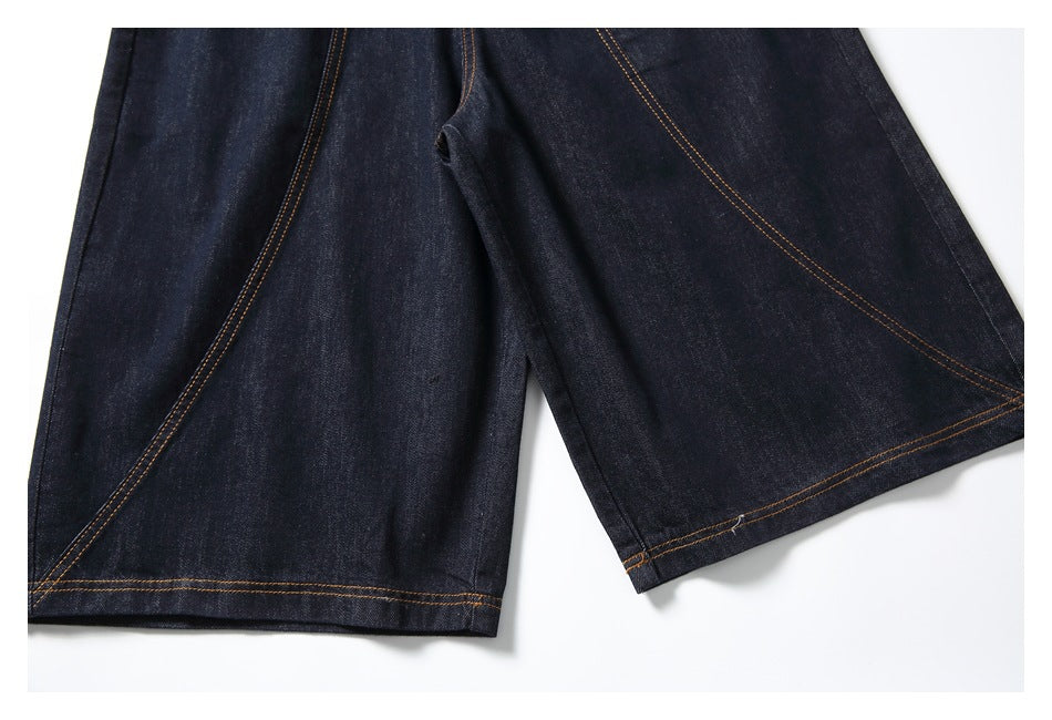 Close-up of the wide dark indigo denim short legs and contrast-stitched hems.