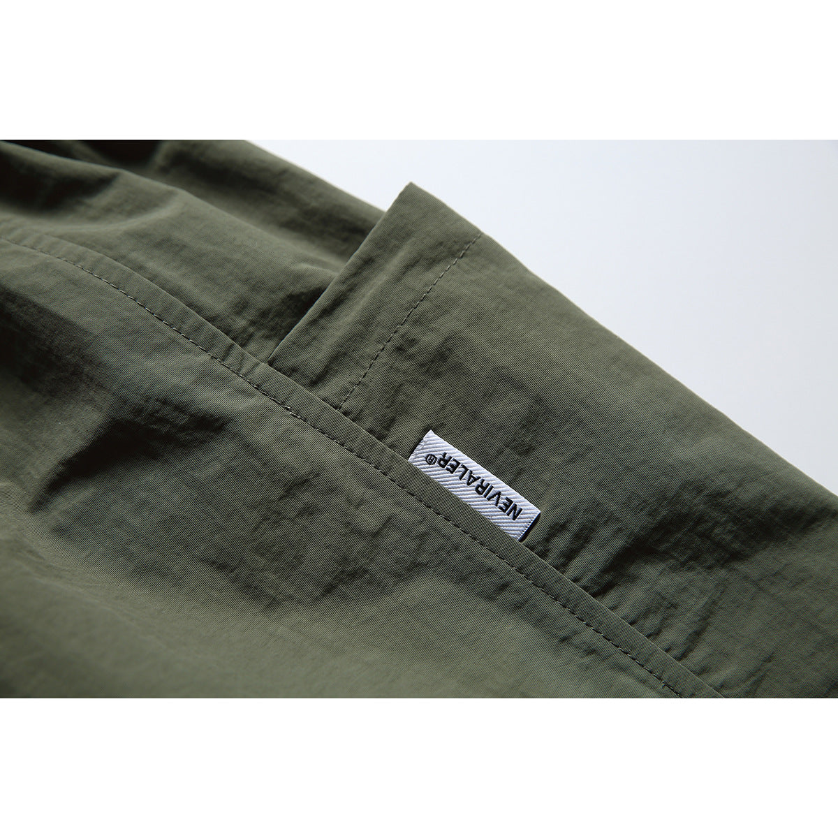 Close-up of an olive-gray shorts pocket with a small woven label.