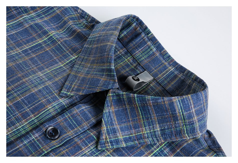 Close-up of a blue multicolored plaid shirt collar, button, and small inner neck label.
