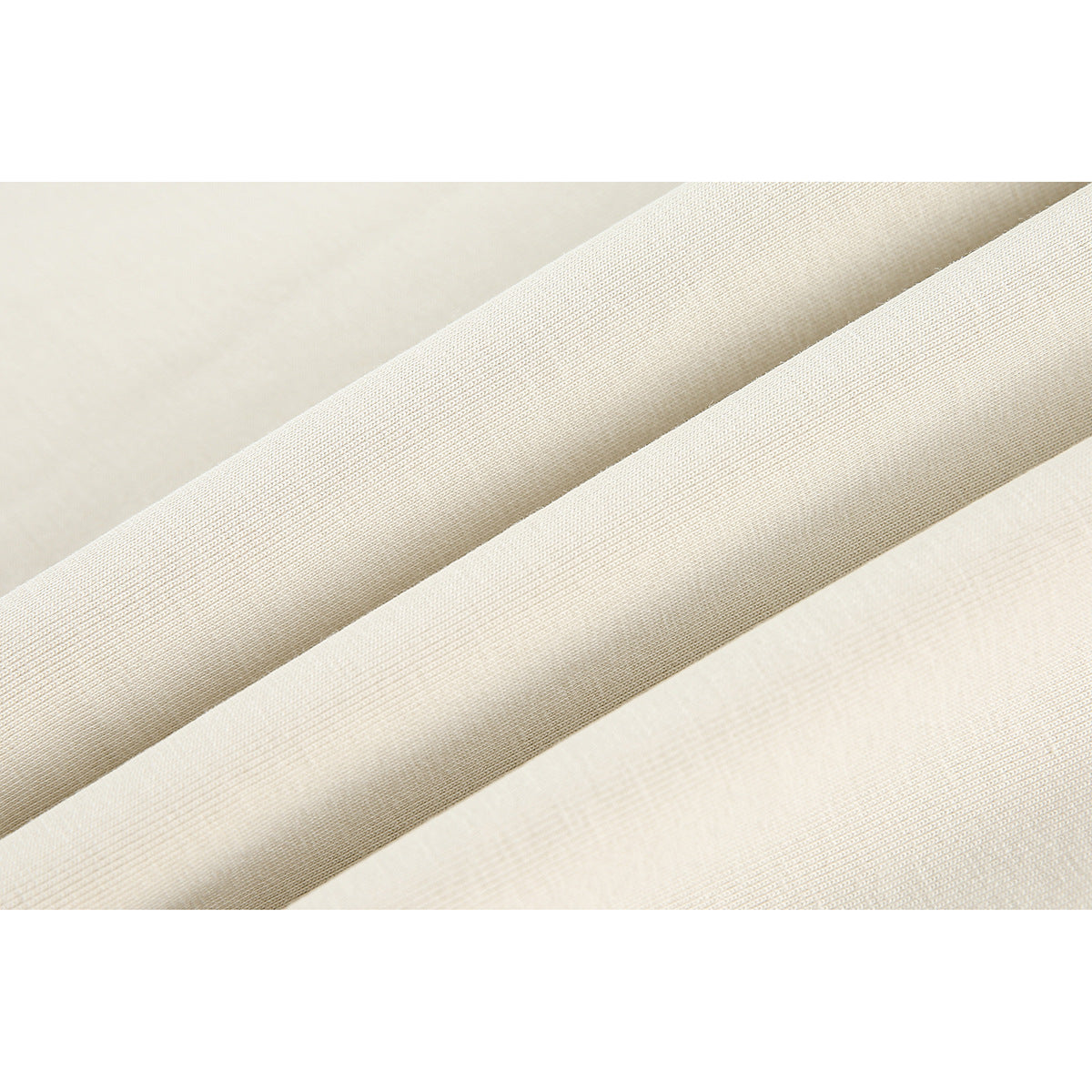 Extreme close-up of cream-colored T-shirt fabric folded into diagonal ridges.