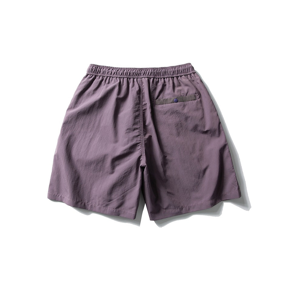 Back view of muted mauve shorts with an elastic waistband and a small buttoned pocket.