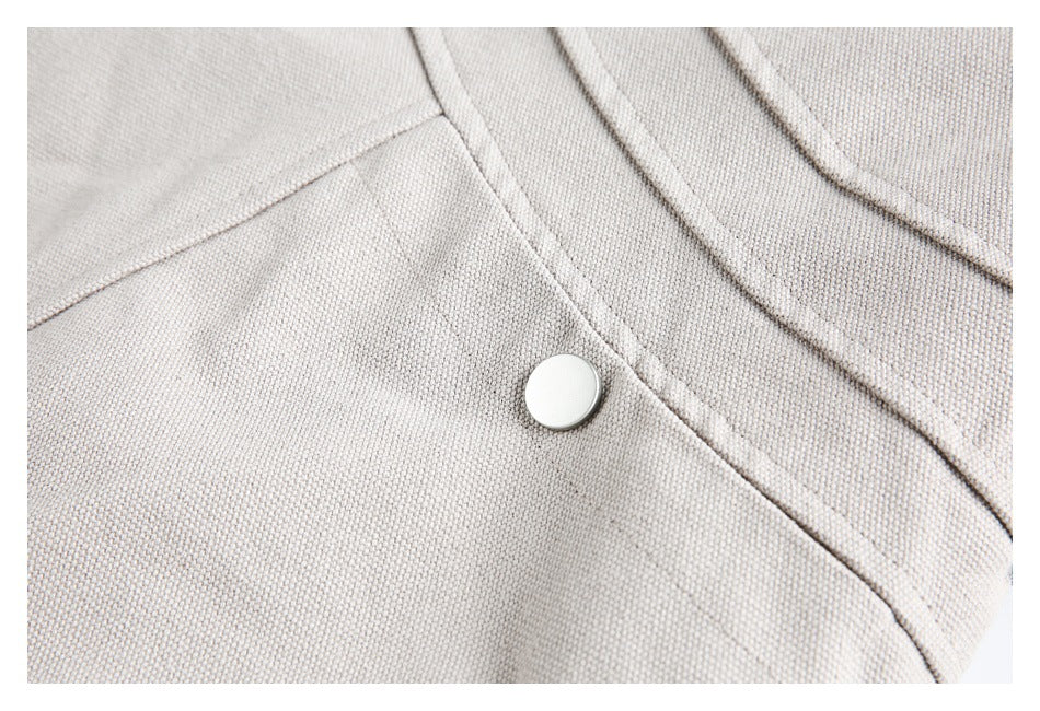 Close-up of a pale taupe-gray textured jacket with a silver snap and stitched seam.