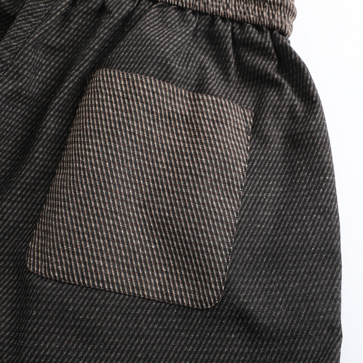 Close-up of a rectangular pocket on dark, finely striped pants.