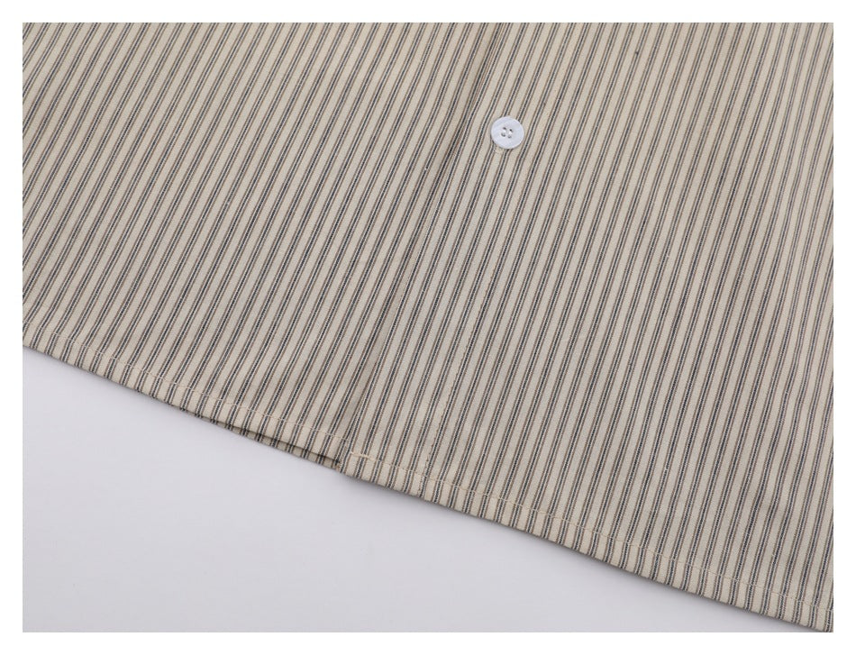 Close-up of a beige striped shirt panel with a white button and stitched hem.