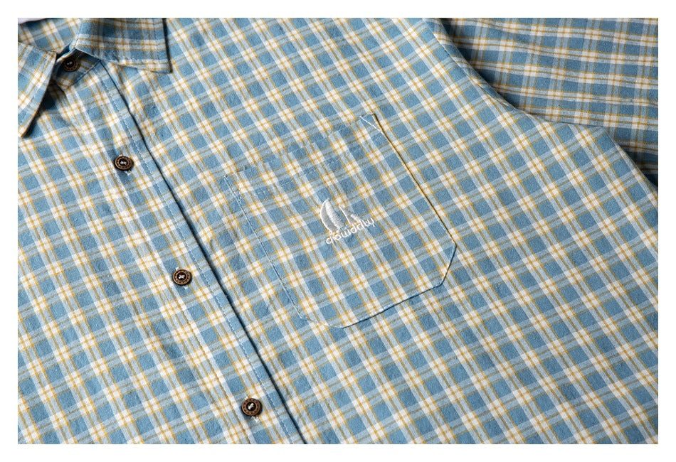 Close-up of the shirt's plaid front pocket with small white embroidered artwork and text.